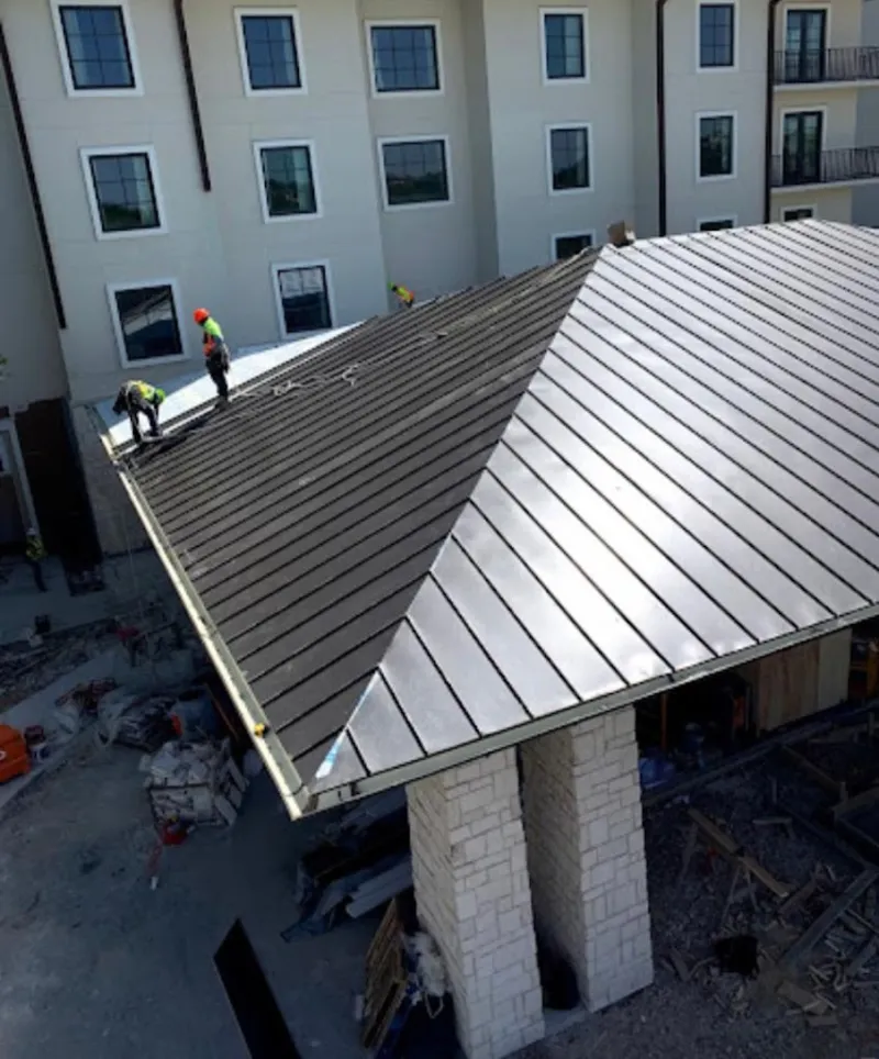 Crew installing standing seam metal roof panels on a commercial project in Valley Falls